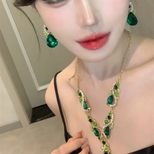 Close-up of vintage gold necklace and teardrop green zircon earrings on a model