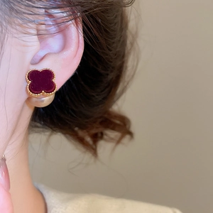 Macro view of burgundy clover stud earrings with gold trim and white pearl backings