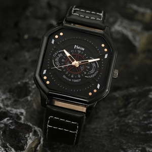 Close-up of a square black quartz watch with rose gold hands on a dark textured rock