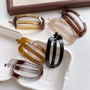 Macro detail of various oval banana hair clips in black, amber, and translucent colors