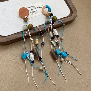 Detailed close-up of Bohemian tassel earrings with turquoise stones and wooden beads