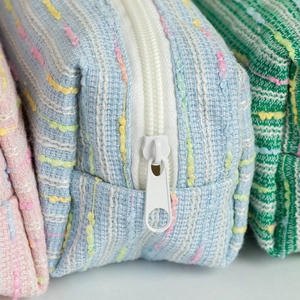Close-up of colorful tweed pencil cases showing woven texture and durable white zippers