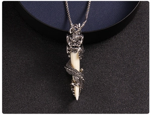 Detailed view of vintage silver dragon coiled around ivory white wolf tooth pendant