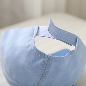 Detail of light blue baseball cap featuring adjustable velcro strap and neat double stitching
