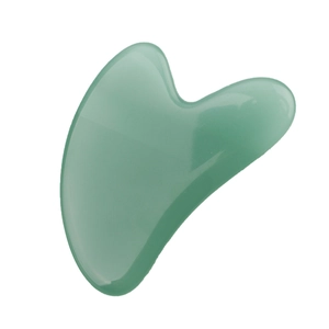 Macro shot of a heart-shaped green jade resin gua sha board with smooth polished edges