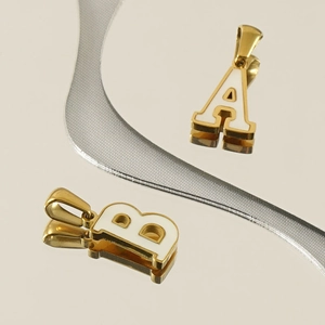 Detail of golden A and B letter pendants with white enamel finish on a reflective surface