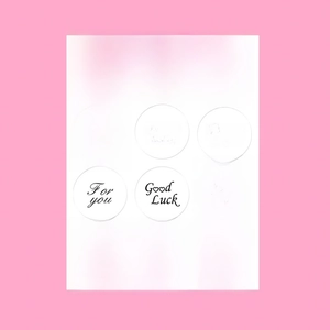 Detailed view of assorted white round thank you labels on a bright pink background