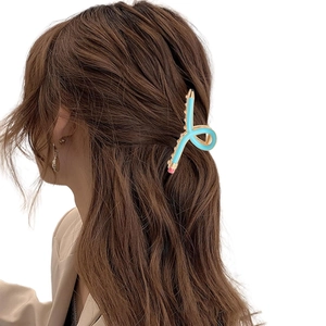 Detail of light blue pencil hair claw clip worn on hair with golden metal teeth