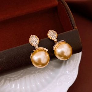 Macro shot of 18k gold plated pearl earrings with sparkling zircon inlay details