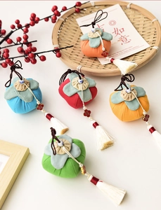 Close-up of fabric persimmon charms with white tassels and festive fortune tags