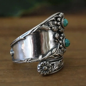 Macro view of vintage silver floral ring featuring sunflower carvings and turquoise stones
