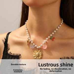 Detail of pearl necklace with gold sunflower, cherry, and heart charms on a lace outfit