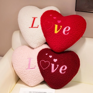 Plush heart-shaped throw pillows with Love embroidery in various colors on a sofa