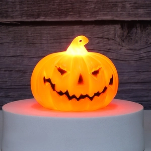 Detail of glowing Halloween pumpkin lamp with warm LED light on a rustic wood background