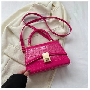 Detail of rose red crocodile embossed faux leather handbag with braided handle and gold lock