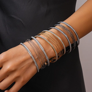 Detail of layered geometric metal bracelets in gold, silver and gunmetal finish