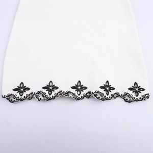 White casual dress featuring black floral embroidery and pearl details on scalloped hemline