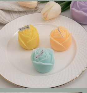 Detailed top view of rose-shaped scented candles in yellow, orange and blue pastel colors