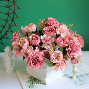 Pink silk roses and peonies in a white square ceramic vase on a green background