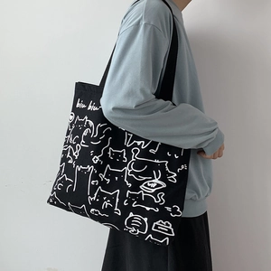 Artistic cat illustration on a black canvas tote bag for women shown as shoulder bag