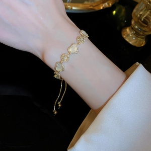 Detail of adjustable gold heart bracelet with cat eye stones and cubic zirconia on wrist