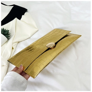 Macro detail of golden rectangular envelope clutch featuring crocodile embossed texture