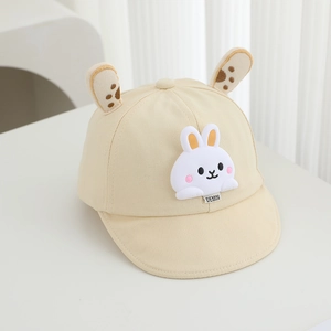 Close-up of beige baby cap with 3D bunny ears and soft cartoon rabbit patch detail