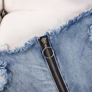 Detailaufnahme des Metallring-Reißverschlusses und der Fransen an den dunkelblauen Shorts