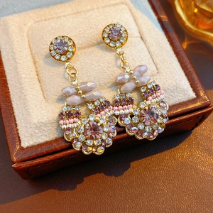 Macro shot of vintage style gold earrings with lavender crystals and sparkling rhinestones