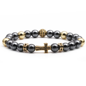 Beaded cross bracelet featuring gold-plated zircon charms and black stone beads on white background