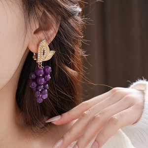 Close-up of vintage French earrings featuring gold bows and purple grape beads on a model