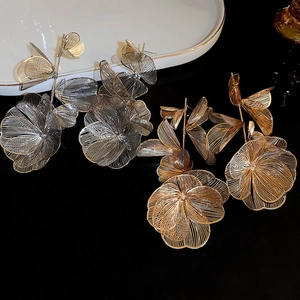 Detail of hollow floral tassel earrings in gold and silver with mesh petal structure