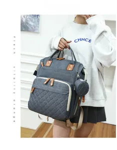 Detail view of grey denim diaper backpack with quilted pattern and round coin purse accessory