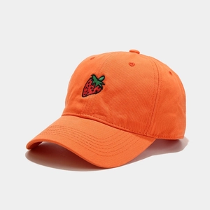 Close-up of strawberry embroidery on vibrant orange cotton baseball cap with twill texture