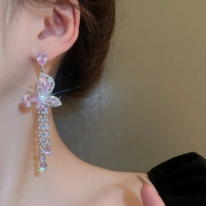 Détail de boucles d'oreilles pendantes avec papillon en cristal rose et zircons brillants