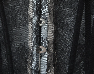Detailed macro view of black lace texture and silver metal busk fasteners on a corset