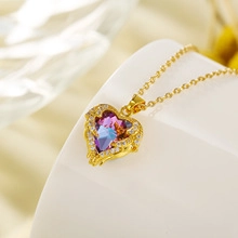 Detail of a heart-shaped gradient crystal pendant with sparkling rhinestones on gold chain