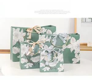 Detail of luxury green floral gift bags in four sizes with elegant ribbon bow handles