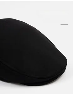 Detail shot of black cotton newsboy cap featuring wide brim design and premium stitching