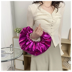 Detail der fuchsiafarbenen Plissee-Handtasche mit Metallic-Finish am Model