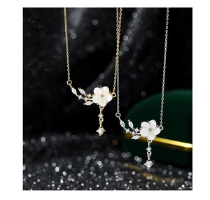 Detailed view of silver and gold flower pendants with mother of pearl and zircon details