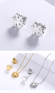 Close-up of snowflake pendant necklaces and stud earrings in gold and silver steel finish