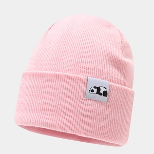 Close-up of pink knit beanie featuring a cute panda patch and soft ribbed texture