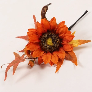 Detailed view of artificial sunflower with autumn maple leaves and berries for decoration