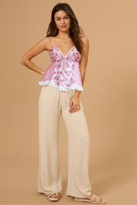 Detail eines rosa geblümten Camisole mit V-Ausschnitt und beiger Leinenhose mit weitem Bein