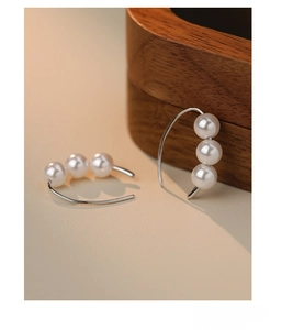 Detailed macro view of S925 sterling silver earrings featuring three elegant white pearls