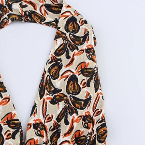 Macro detail of abstract floral print and crepe texture on a beige halter neck top