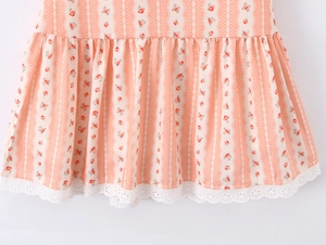 Dettaglio dell'orlo floreale a righe con pizzo bianco su un abito rosa in stile francese