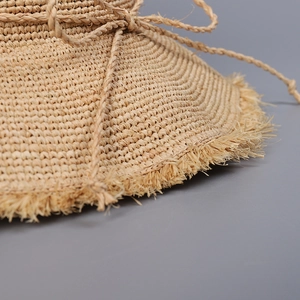 Handmade raffia straw sun hat with frayed fringe edges and twisted rope bow detail