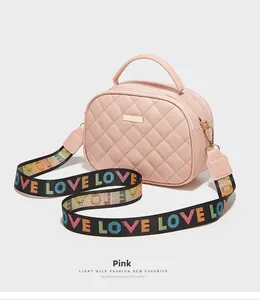 Detalle del bolso de cuero acolchado rosa con correa ancha tejida y tipografía LOVE